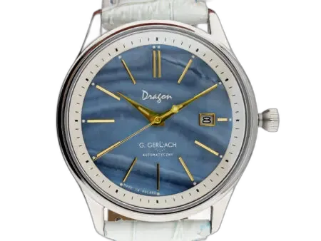 Zegarek męski G. Gerlach Dragon z niebieską tarczą o unikalnej, falistej fakturze przypominającej powierzchnię wody. Na tarczy umieszczono złote, smukłe indeksy godzinowe oraz eleganckie, złote wskazówki, które dodają zegarkowi klasycznego charakteru. Na godzinie 3 znajduje się złota ramka z datownikiem wskazującym dzień miesiąca na białym tle. Logo "Dragon" umieszczono pod godziną 12, natomiast napis "G. Gerlach Automatyczny" znajduje się powyżej godziny 6. Srebrna koperta o klasycznym kształcie współgra z niebieską tarczą, a dopasowany biały pasek ze skóry krokodyla dodaje elegancji. Koronka znajduje się po prawej stronie koperty, co podkreśla tradycyjny styl tego modelu.